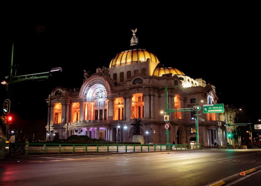 Mexico Bellas Artes - a large building with a gold domed roof at night