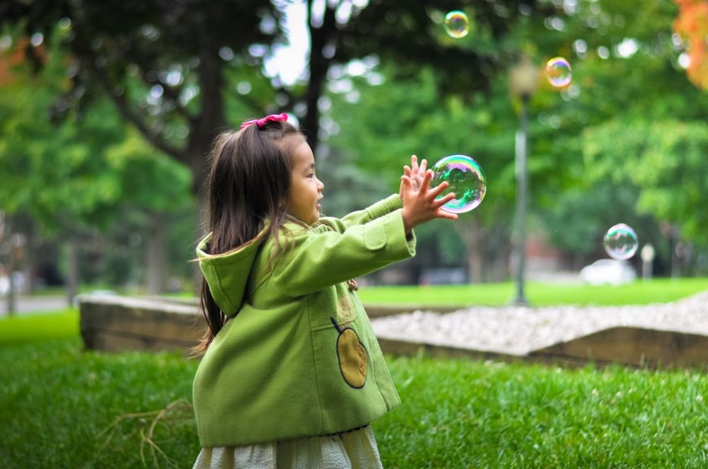 Family Park - selective photo of a girl holding bubbles