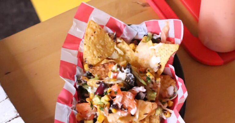 Mexican Dishes - From above of Mexican fast food with tortilla chips and vegetables topped with cheese sauce served on plate with paper on table in cafe